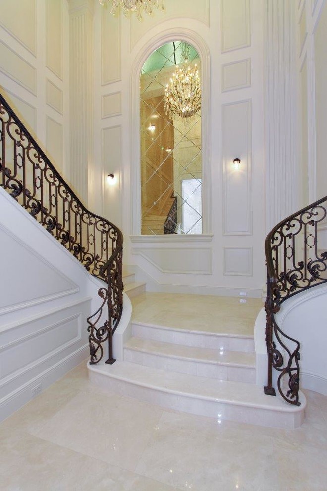 Diseño de escalera curva clásica extra grande con escalones de mármol, contrahuellas de mármol y barandilla de metal