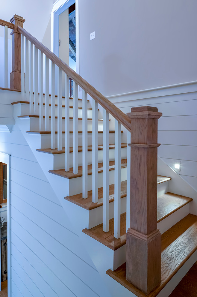 На фото: большая п-образная лестница в стиле кантри с деревянными ступенями, крашенными деревянными подступенками и деревянными перилами с
