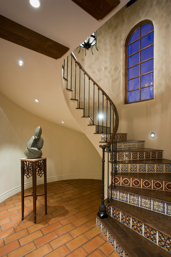 Идея дизайна: изогнутая лестница в средиземноморском стиле с деревянными ступенями и подступенками из плитки