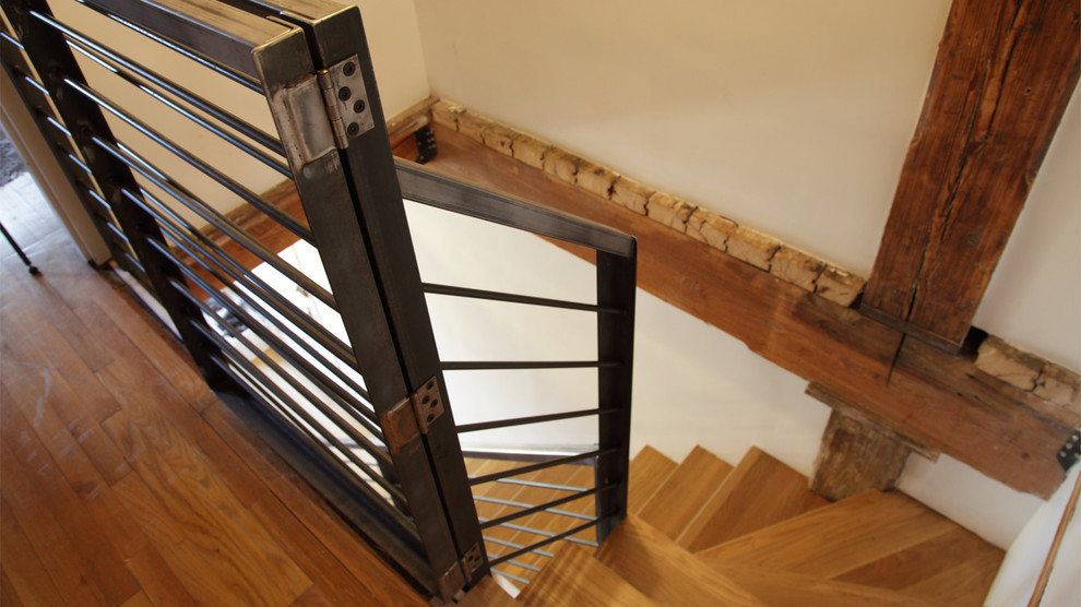 Foto de escalera suspendida industrial grande con escalones de madera, contrahuellas de madera y barandilla de metal