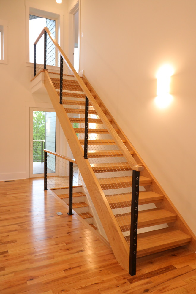 Ejemplo de escalera recta minimalista pequeña con escalones de madera, contrahuellas de madera y barandilla de cable