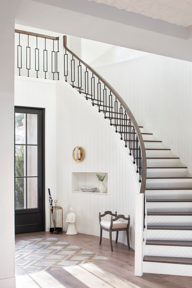 Стильный дизайн: изогнутая лестница в стиле неоклассика (современная классика) с деревянными ступенями, крашенными деревянными подступенками и перилами из смешанных материалов - последний тренд