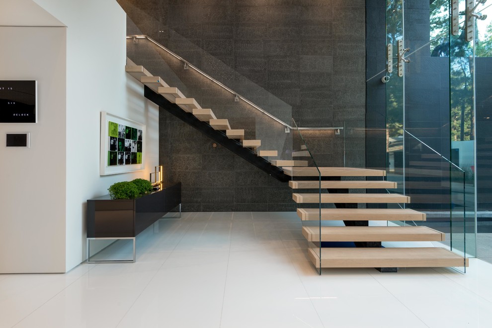 На фото: огромная угловая лестница в стиле модернизм с деревянными ступенями и стеклянными перилами без подступенок с
