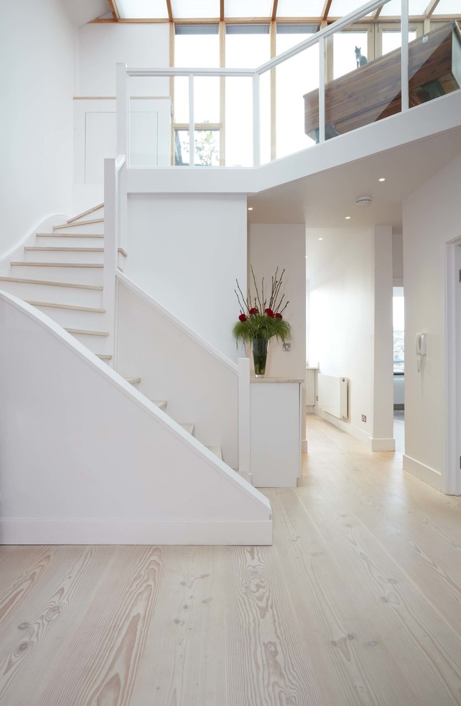 Bild på en mellanstor minimalistisk svängd trappa i trä, med sättsteg i målat trä
