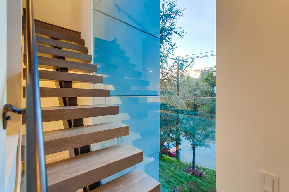Exemple d'un grand escalier sans contremarche droit tendance avec des marches en bois et un garde-corps en verre.
