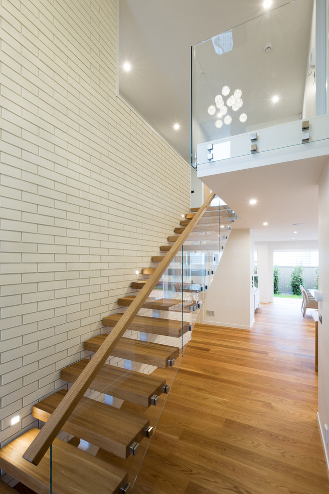 Photo of a large contemporary wood floating staircase in Auckland with open risers.