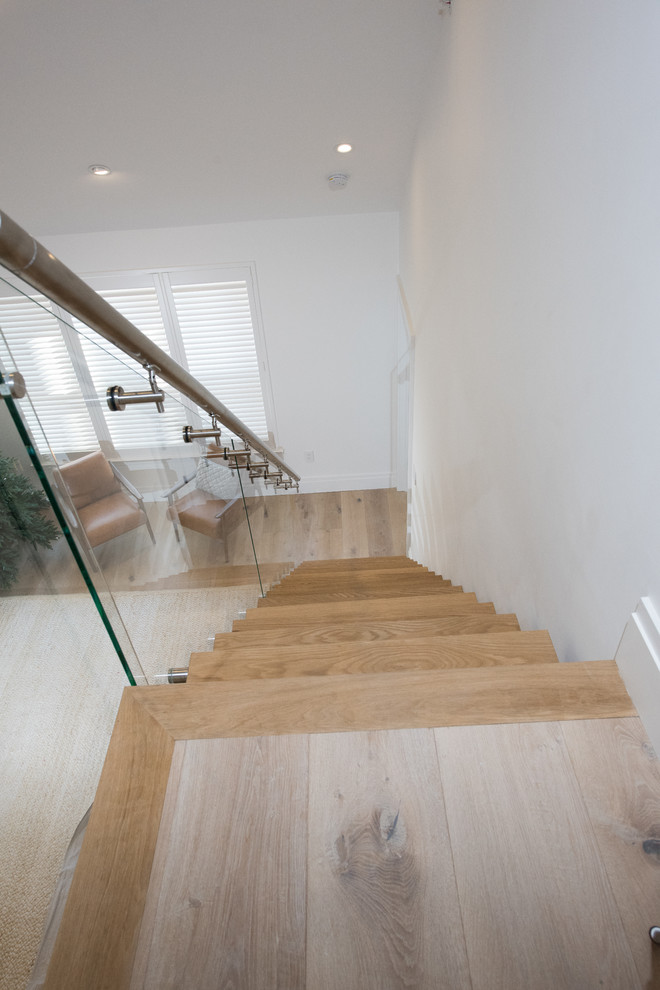 Inspiration for a large contemporary wood straight glass railing staircase in New York with open risers.