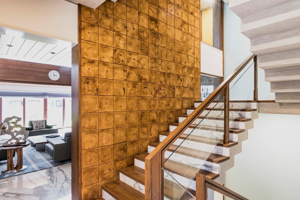 Foto de escalera en U asiática con escalones de madera, contrahuellas de mármol y barandilla de vidrio