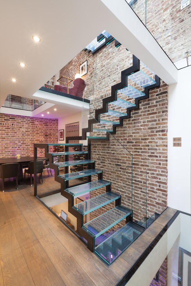 Photo of an urban glass u-shaped glass railing staircase in London with open risers and feature lighting.