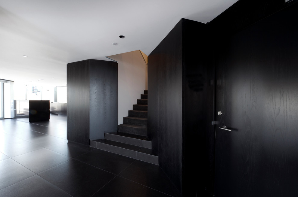 Imagen de escalera en U contemporánea de tamaño medio con escalones con baldosas, contrahuellas con baldosas y/o azulejos y barandilla de madera