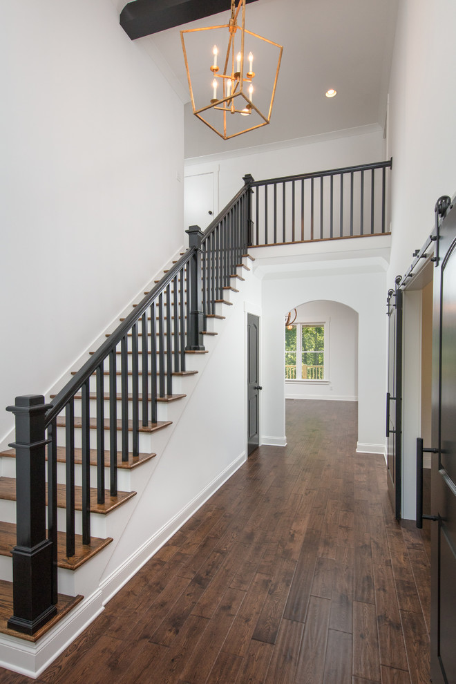 Пример оригинального дизайна: большая прямая лестница в классическом стиле с деревянными ступенями, деревянными перилами и крашенными деревянными подступенками