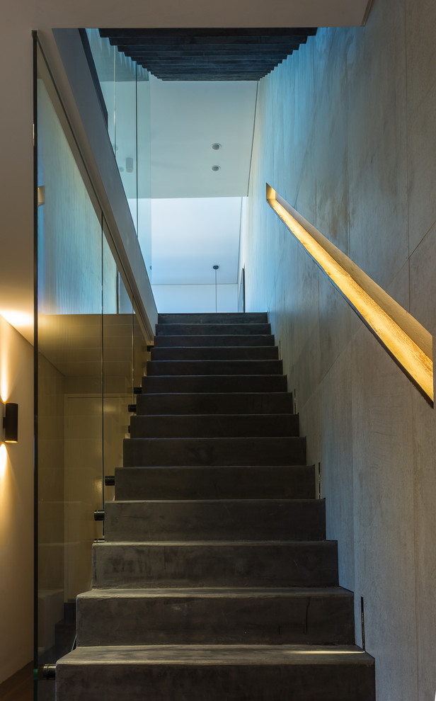 Ejemplo de escalera recta urbana pequeña con escalones de hormigón, contrahuellas de hormigón y barandilla de vidrio