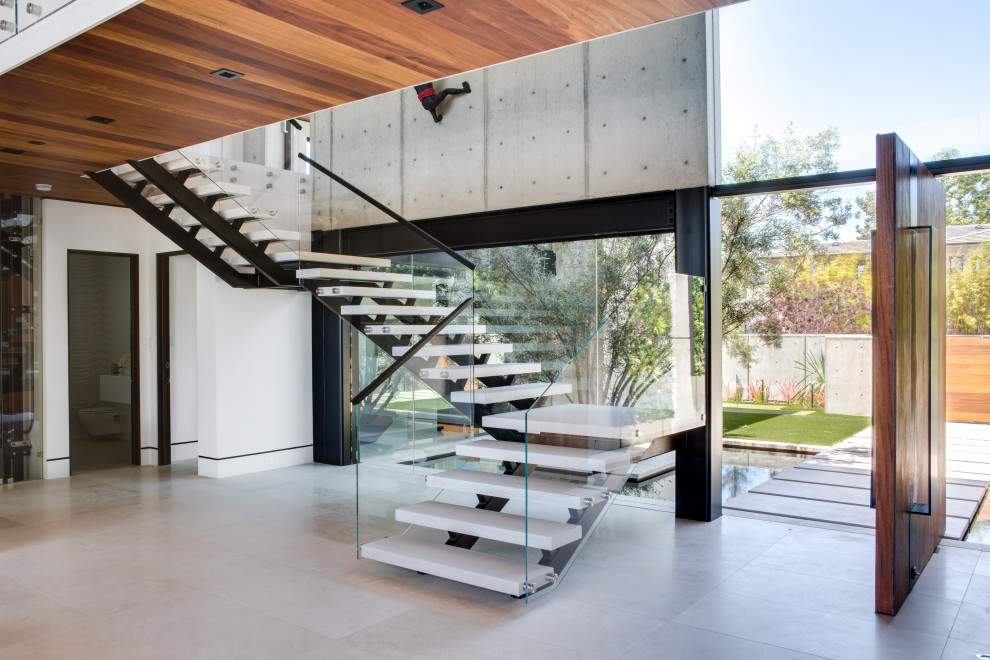 Стильный дизайн: лестница на больцах в современном стиле с стеклянными перилами без подступенок - последний тренд