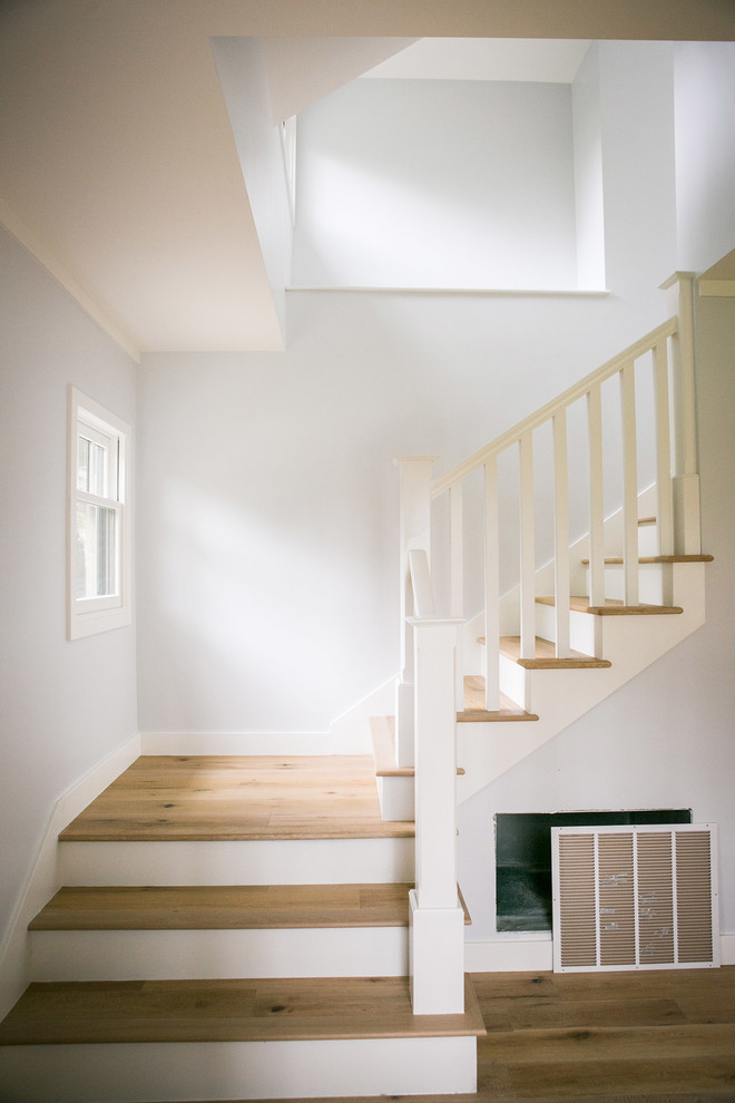 Пример оригинального дизайна: угловая лестница среднего размера в современном стиле с деревянными ступенями, крашенными деревянными подступенками и деревянными перилами