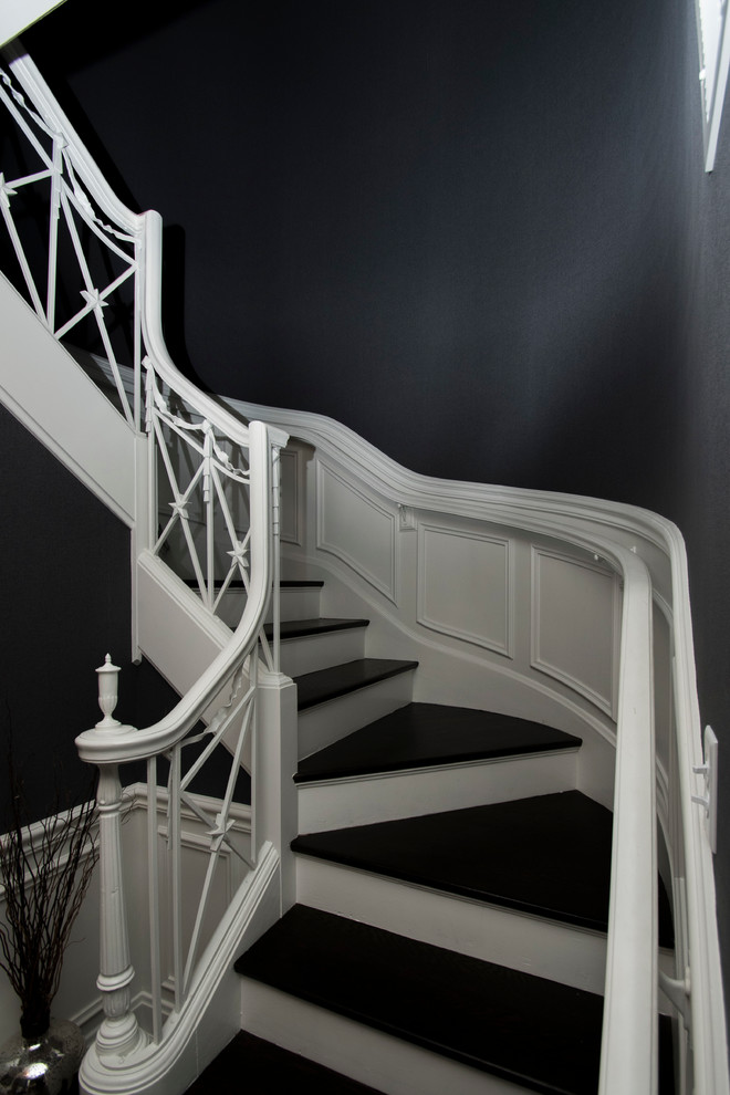 Diseño de escalera curva clásica con escalones de madera y contrahuellas de madera pintada