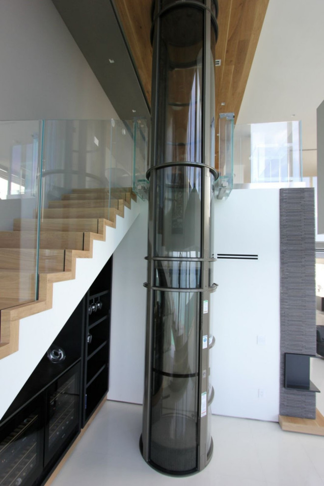 Cette image montre un grand escalier minimaliste en L avec des marches en bois, des contremarches en bois, un garde-corps en verre et du papier peint.