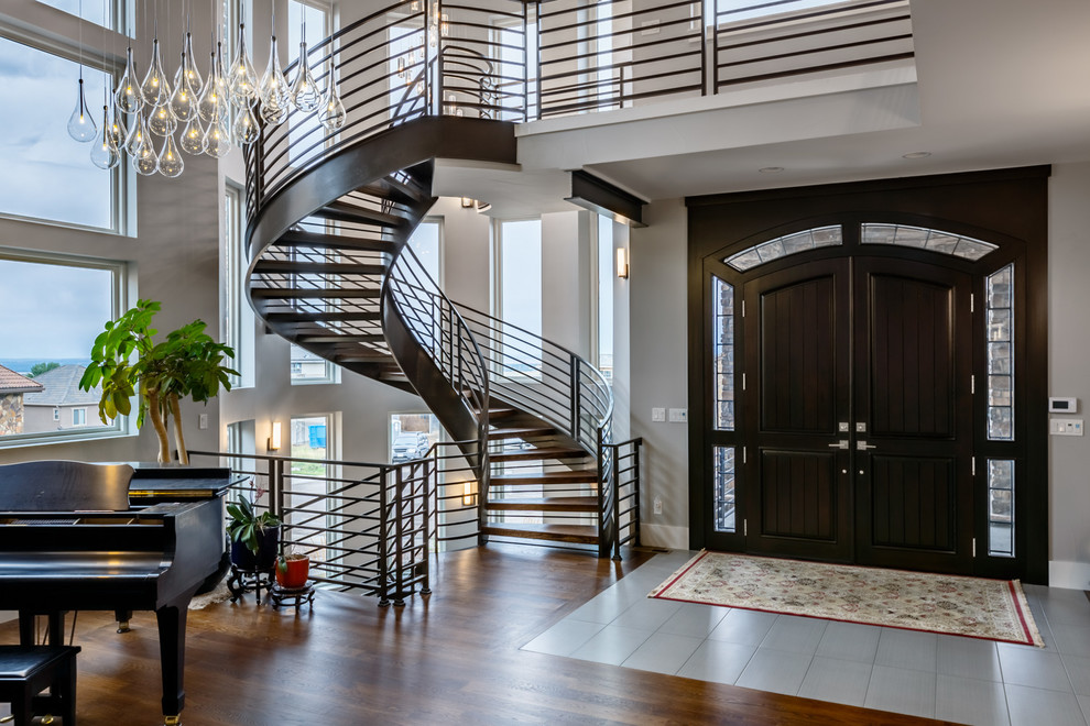 Идея дизайна: изогнутая лестница в стиле неоклассика (современная классика) с деревянными ступенями и металлическими перилами без подступенок