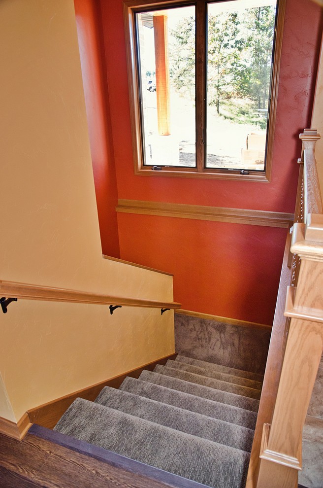 他の地域にある高級な中くらいなトラディショナルスタイルのおしゃれな階段 (カーペット張りの蹴込み板、木材の手すり) の写真