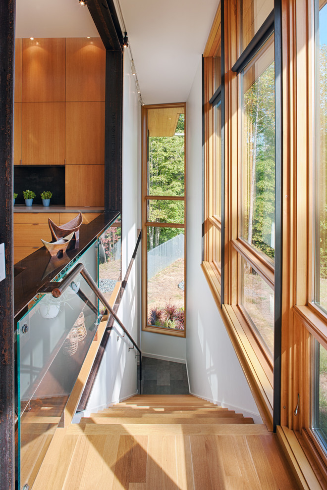 Cette image montre un escalier droit minimaliste avec des marches en bois et un garde-corps en métal.