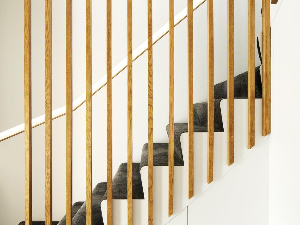 Immagine di una scala a "L" moderna di medie dimensioni con pedata in moquette, alzata in moquette e parapetto in legno