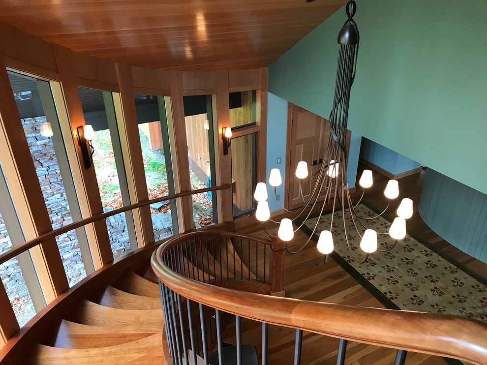 Стильный дизайн: большая изогнутая лестница в классическом стиле с деревянными ступенями и металлическими перилами - последний тренд