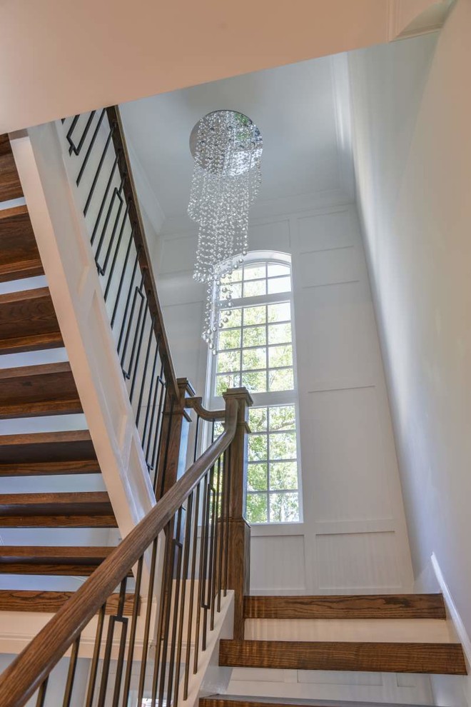 Ejemplo de escalera suspendida de estilo americano grande sin contrahuella con escalones de madera y barandilla de metal