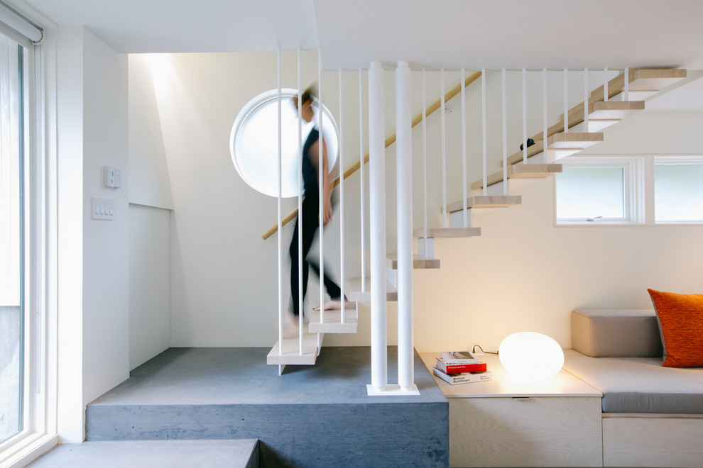 Идея дизайна: лестница на больцах в современном стиле с деревянными ступенями, перилами из тросов и кладовкой или шкафом под ней без подступенок