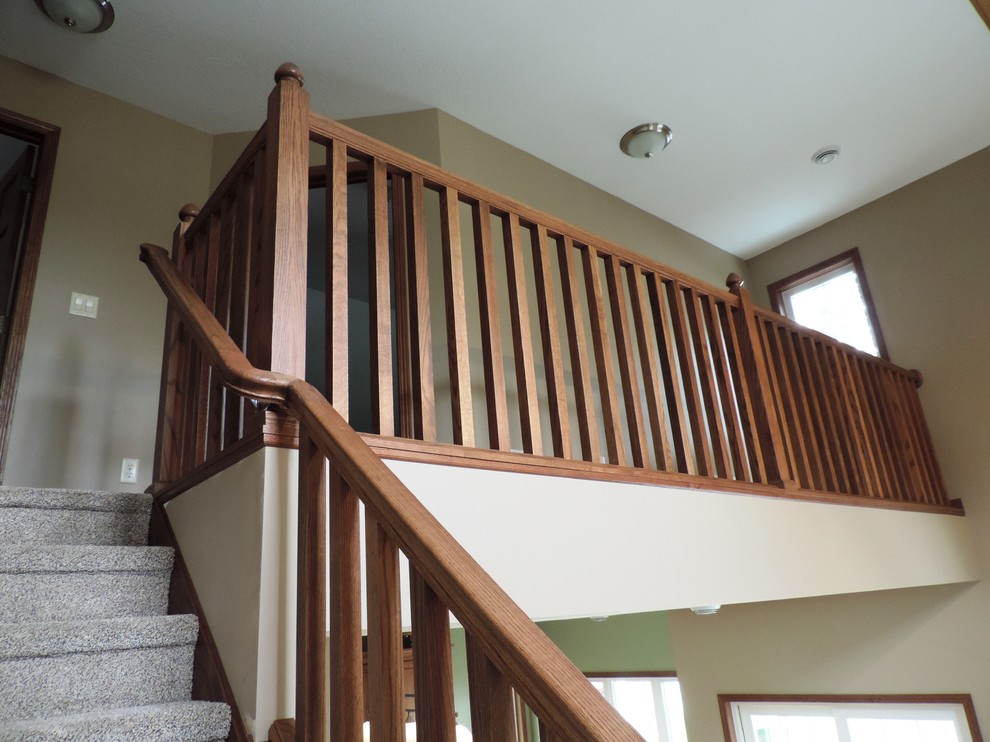 Foto de escalera en U rústica de tamaño medio con escalones enmoquetados, contrahuellas enmoquetadas y barandilla de madera
