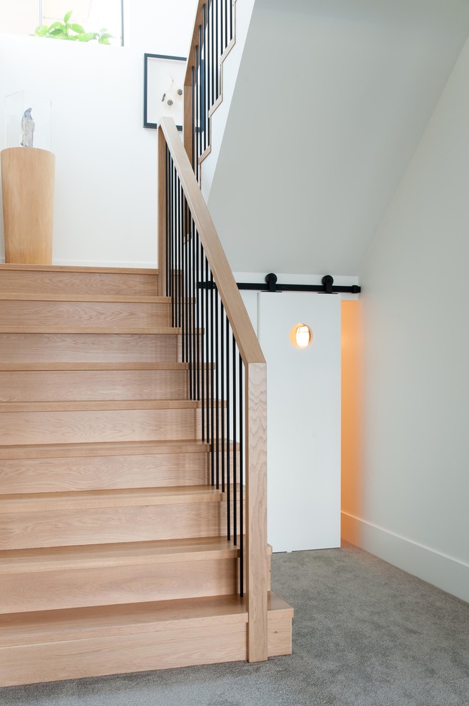 Ejemplo de escalera en U escandinava con escalones de madera, contrahuellas de madera y barandilla de varios materiales