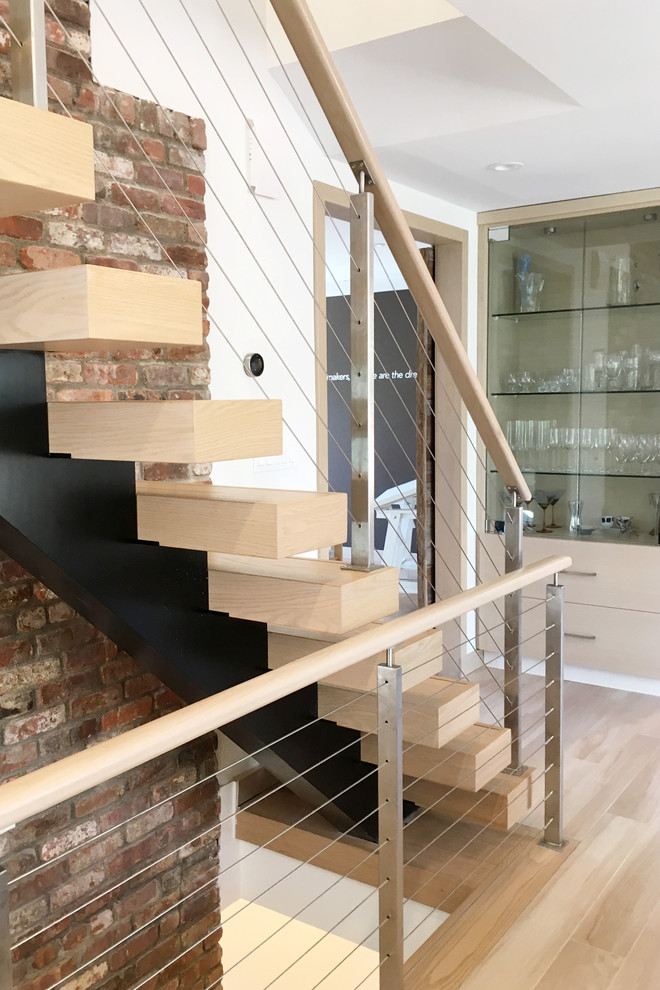 На фото: прямая лестница среднего размера в стиле модернизм с деревянными ступенями и перилами из тросов без подступенок с