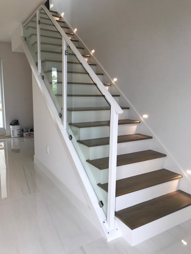 This is an example of a contemporary wood straight glass railing staircase in Orlando with painted wood risers.