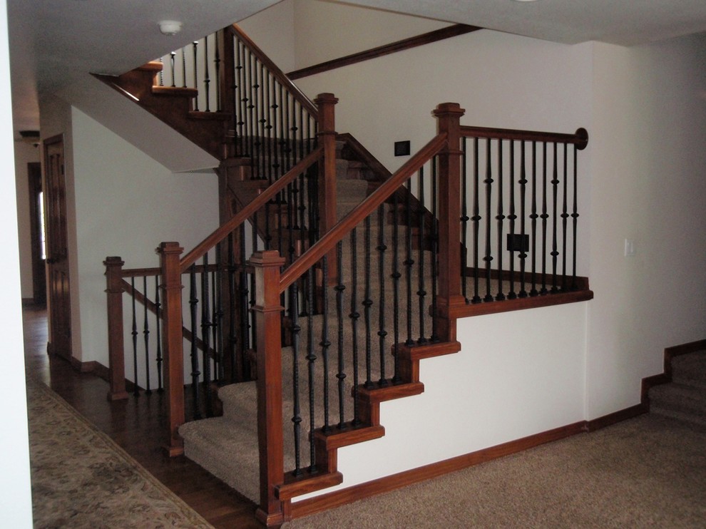 Ejemplo de escalera en L tradicional de tamaño medio con escalones enmoquetados, contrahuellas enmoquetadas y barandilla de metal