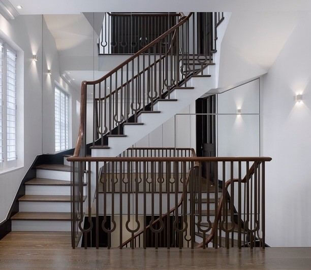 Пример оригинального дизайна: огромная п-образная лестница в классическом стиле с деревянными ступенями, крашенными деревянными подступенками и металлическими перилами