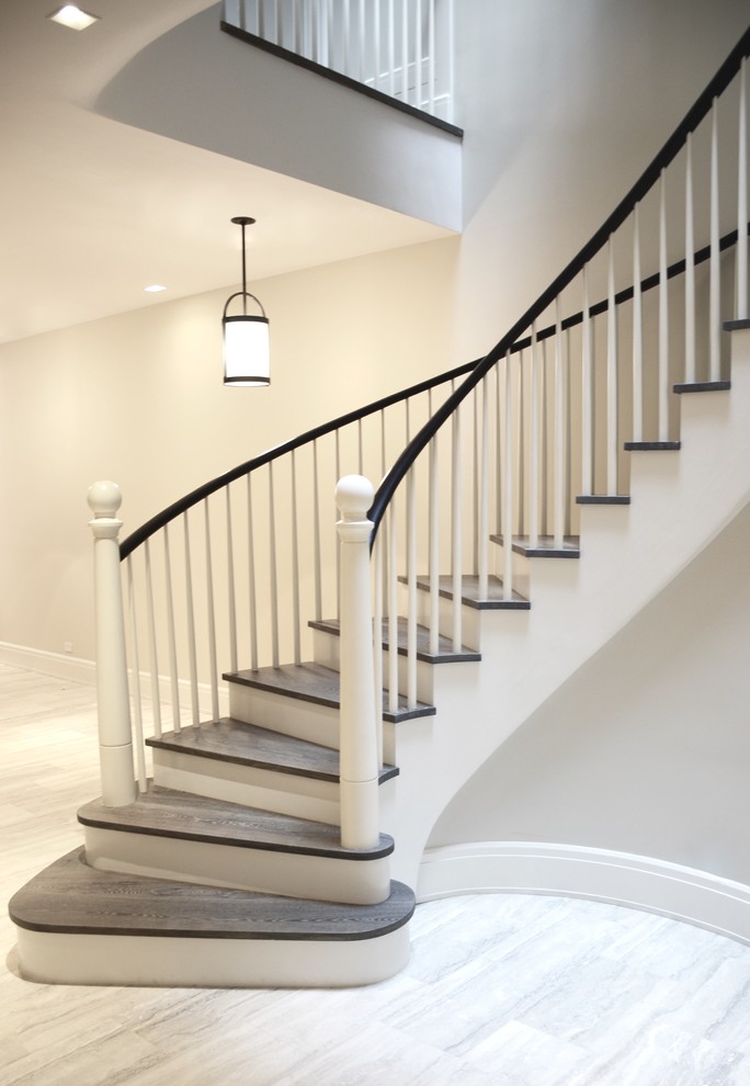 Large traditional wood curved wood railing staircase in Other with painted wood risers.
