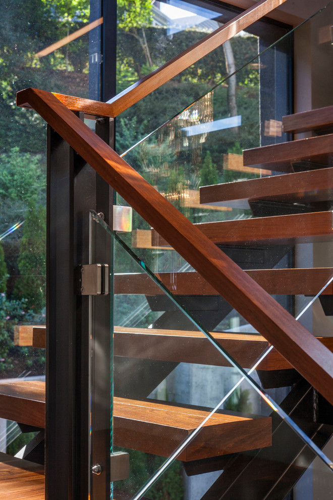 Modelo de escalera curva actual grande con escalones de madera, contrahuellas de vidrio y barandilla de madera