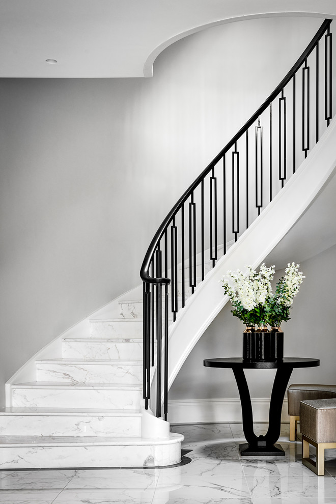 На фото: огромная винтовая лестница в современном стиле с мраморными ступенями и металлическими перилами