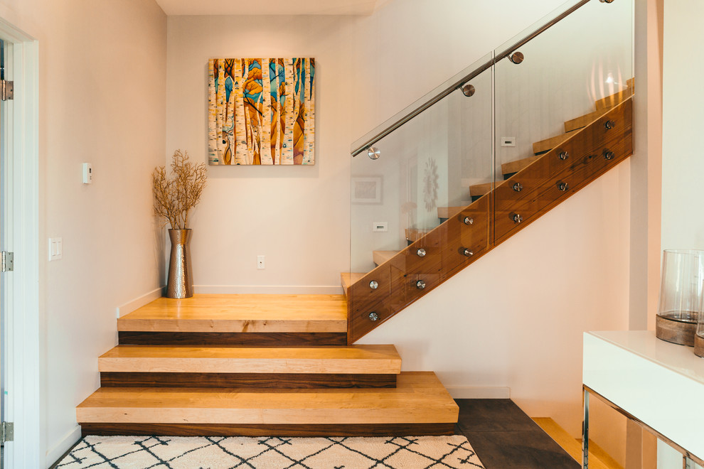 Cette image montre un escalier sans contremarche design en L de taille moyenne avec des marches en bois et un garde-corps en verre.