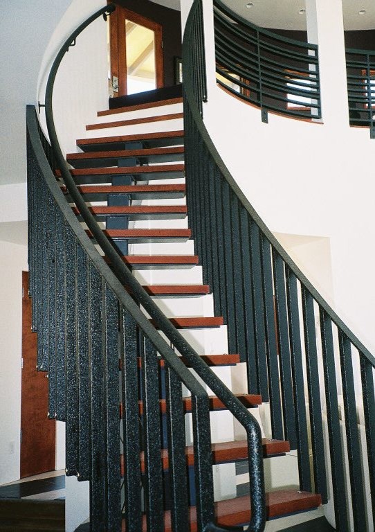 Imagen de escalera curva moderna sin contrahuella con escalones de madera y barandilla de metal