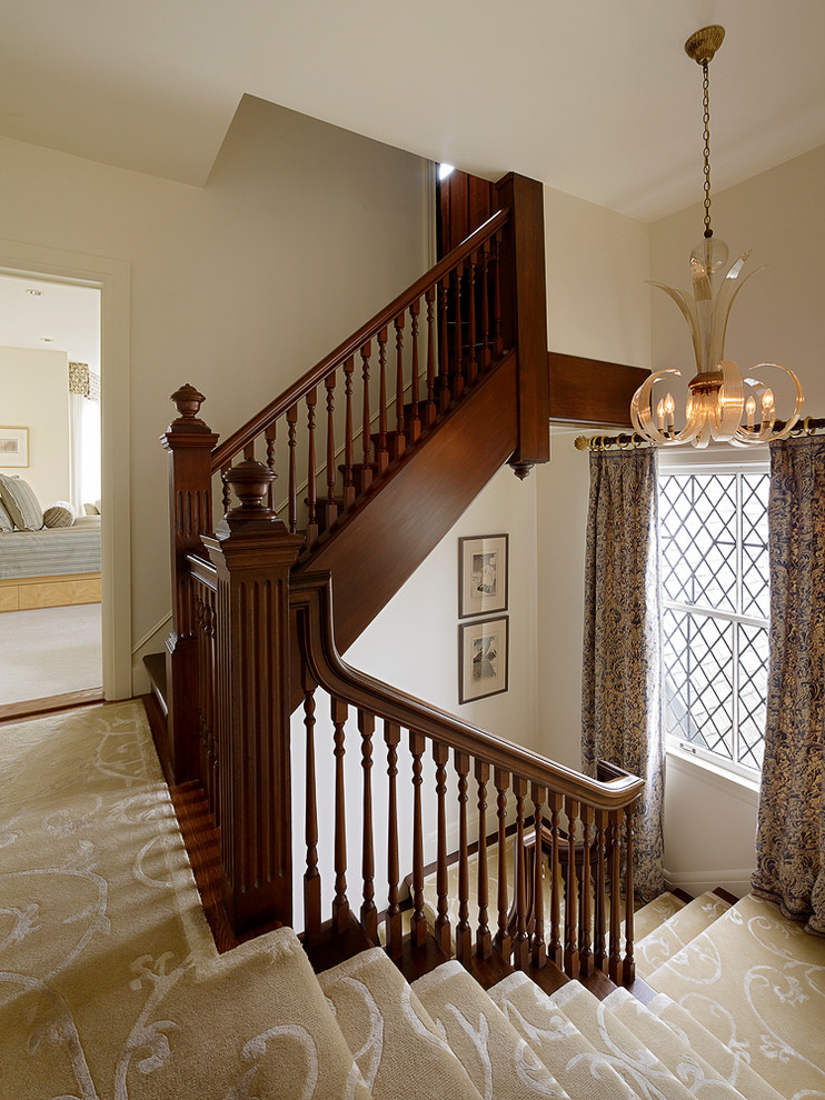 Cette image montre un grand escalier traditionnel en U avec des marches en bois.