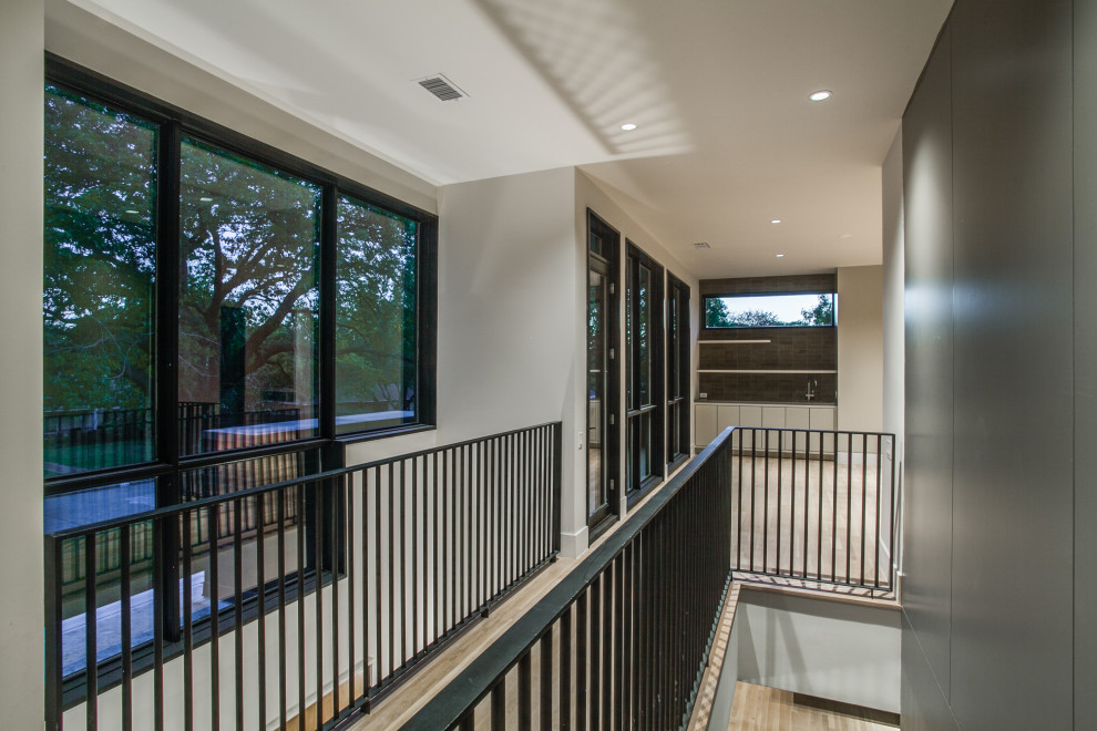 На фото: прямая лестница среднего размера в стиле модернизм с деревянными ступенями, металлическими перилами и панелями на части стены без подступенок с