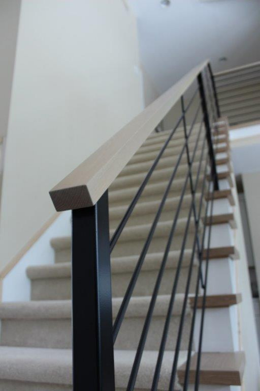 Imagen de escalera recta actual de tamaño medio con escalones enmoquetados, contrahuellas enmoquetadas y barandilla de metal