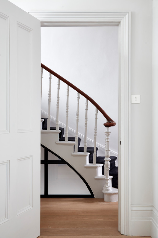 Foto de escalera curva clásica grande con escalones de madera pintada, contrahuellas de madera pintada y barandilla de madera