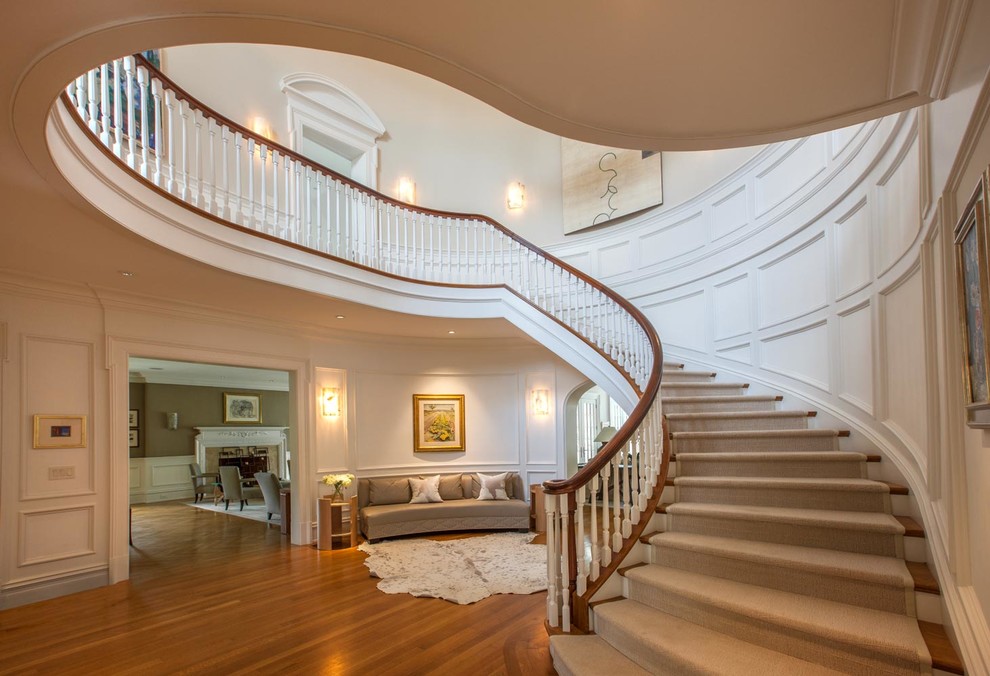 Идея дизайна: огромная лестница в классическом стиле с деревянными ступенями и крашенными деревянными подступенками
