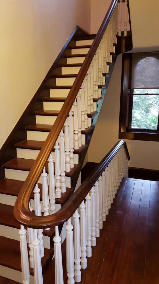 Modelo de escalera en U tradicional de tamaño medio con escalones de madera, contrahuellas de madera pintada y barandilla de madera