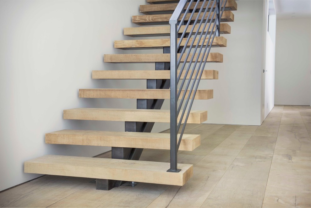 Example of a large minimalist wooden floating staircase design in Denver with metal risers
