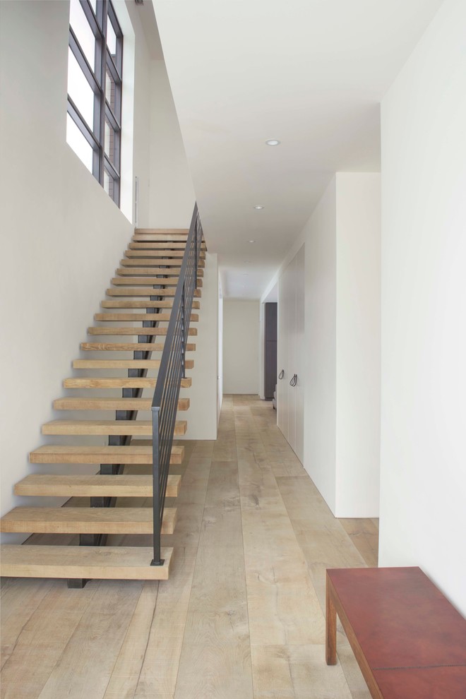Diseño de escalera suspendida minimalista grande con escalones de madera y contrahuellas de metal