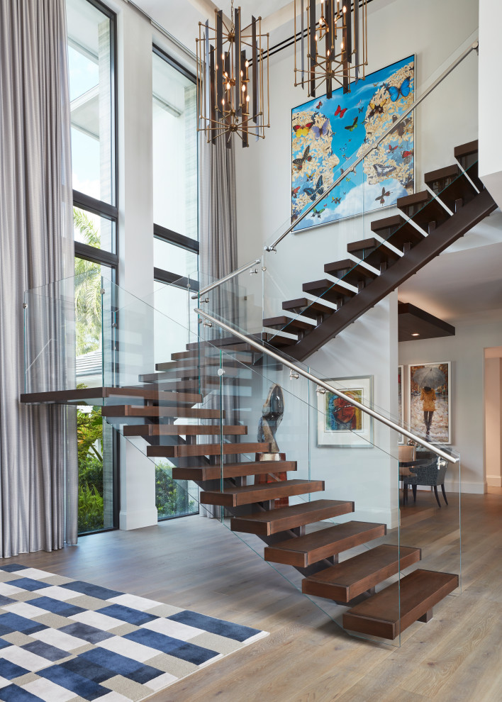 Cette image montre un escalier sans contremarche design en U avec des marches en bois et un garde-corps en verre.
