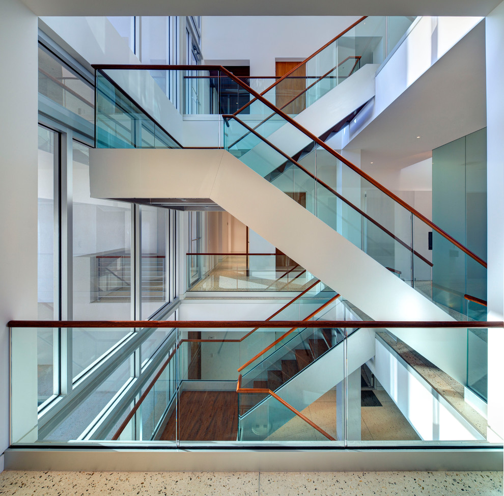 Источник вдохновения для домашнего уюта: большая лестница в стиле модернизм с деревянными ступенями и стеклянными перилами