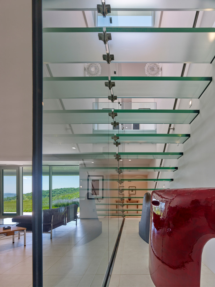 Immagine di una grande scala sospesa moderna con pedata in vetro, nessuna alzata e parapetto in vetro