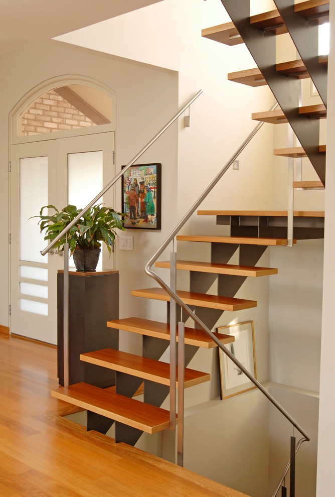 This is an example of a contemporary wood staircase in Miami with open risers and feature lighting.